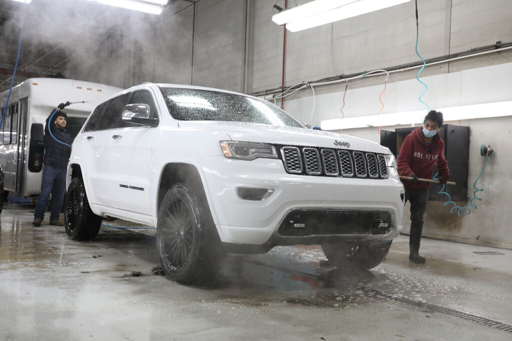 Crystal Clean employees spraying down a white Jeep Cherokee